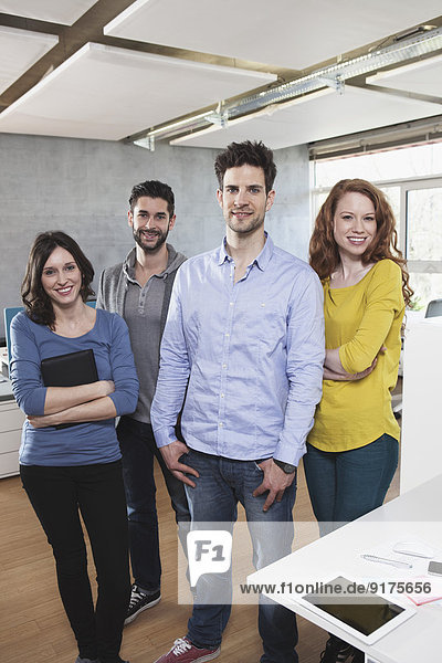Gruppenbild von vier im Büro stehenden Kollegen