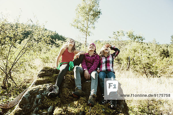 Three girls siting on rock in nature