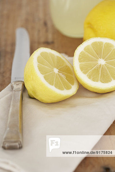 Geschnittene Zitrone  Messer  Tuch und Glas Zitronensaft auf Holz