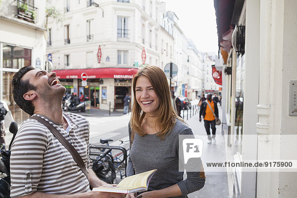 Frankreich  Paris  Portrait eines glücklichen Paares  das die Stadt mit einem Reiseführer erkundet.