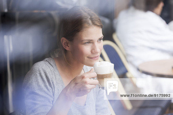 Frankreich  Paris  Porträt einer jungen Frau  die in einem Café Milchkaffee trinkt.
