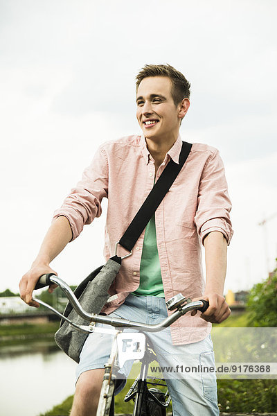 Porträt eines lächelnden jungen Mannes auf dem Fahrrad