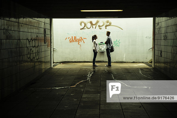Young couple standing face to face in a dark underpass