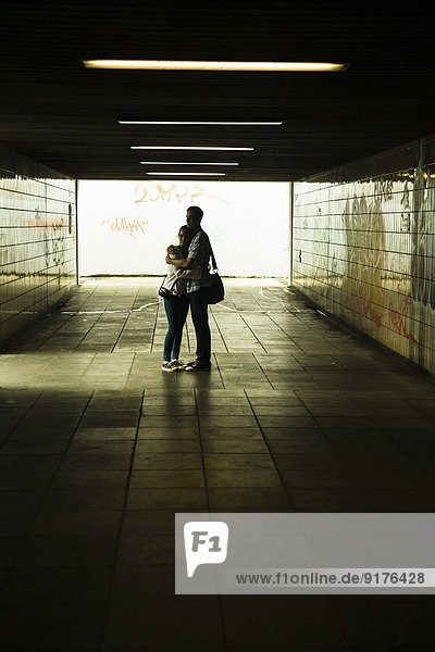 Young couple hugging each other in a dark underpass