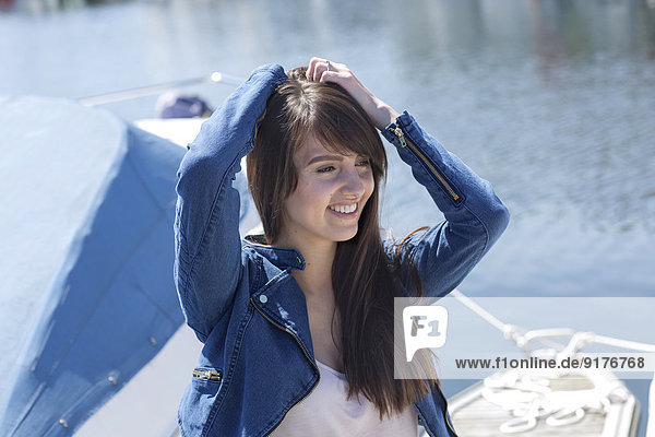 Porträt der lächelnden jungen Frau auf dem Boot vor dem Wasser
