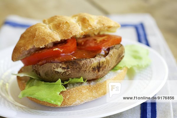 Gegrillter Portobello-Pilz-Burger mit Tomate und Salat auf dem Teller