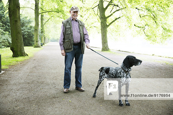 Senior man walking with his German Shorthaired Pointer in city park