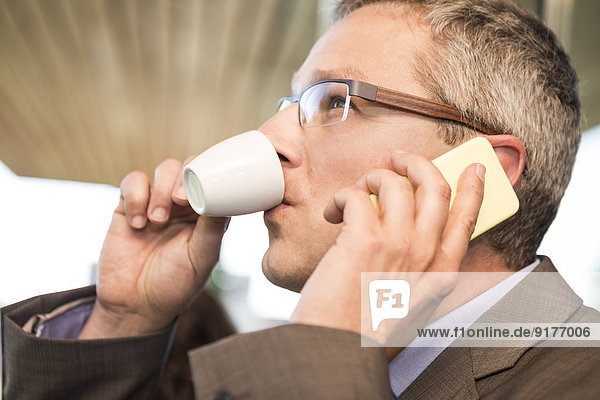 Businessman on cell phone drinking coffee