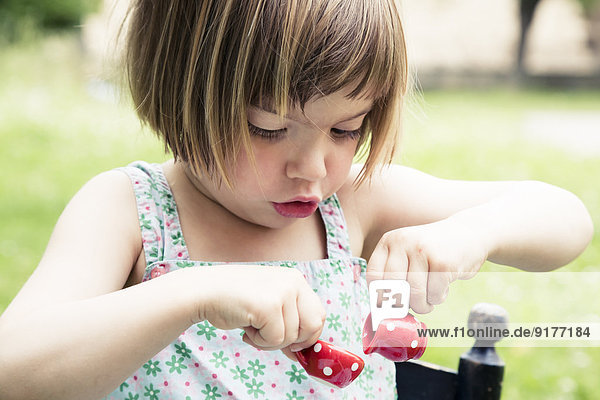 Porträt eines kleinen Mädchens beim Spielen mit Puppenporzellan im Garten