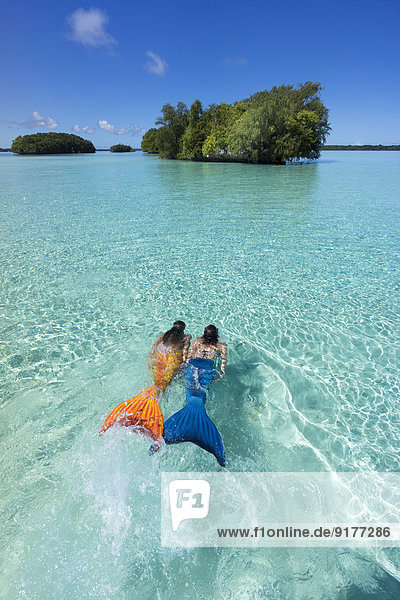 Palau  zwei junge Frauen in Meerjungfrau-Kostüm schwimmend in einer Lagune