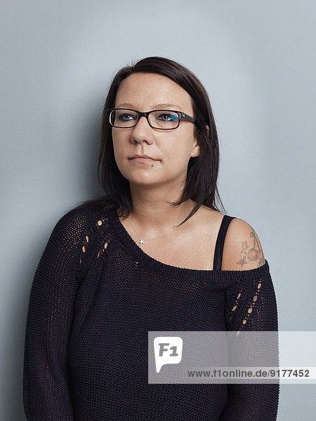 Bildnis der brünetten Frau mit Brille vor grauem Hintergrund