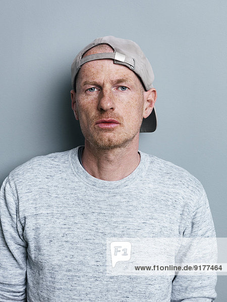 Portrait of man with basecap in front of gray background