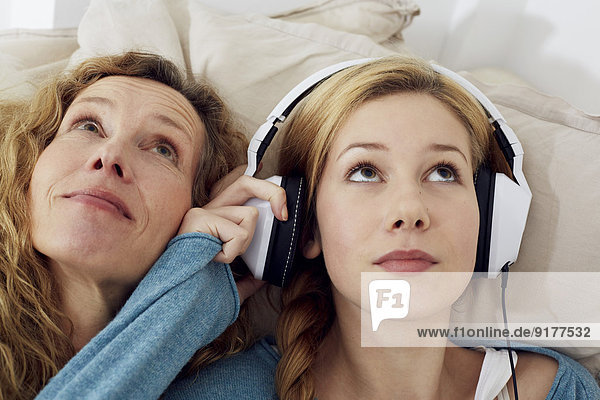Portrait von Mutter und Tochter beim Musikhören mit Kopfhörern zu Hause