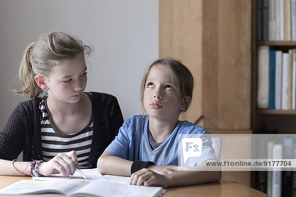 Schwester hilft ihrem kleinen Bruder  indem sie seine Hausaufgaben macht.
