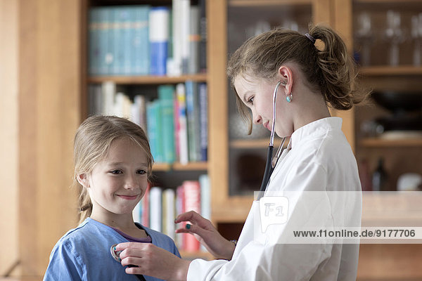 Bruder und Schwester spielen Arzt mit Stethoskop und Weißkittel