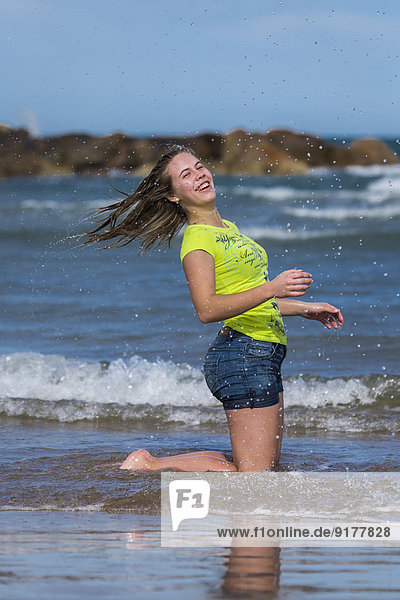 Weibliche Teenager haben Spaß am Ufer des Strandes