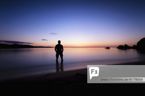 Spain  Menorca  Man watching sunset at Playa de Cavalleria