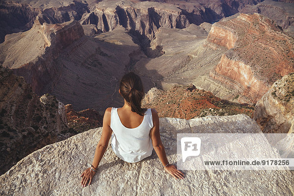 USA  Arizona  woman sitting at cliff of Grand Canyon  back view
