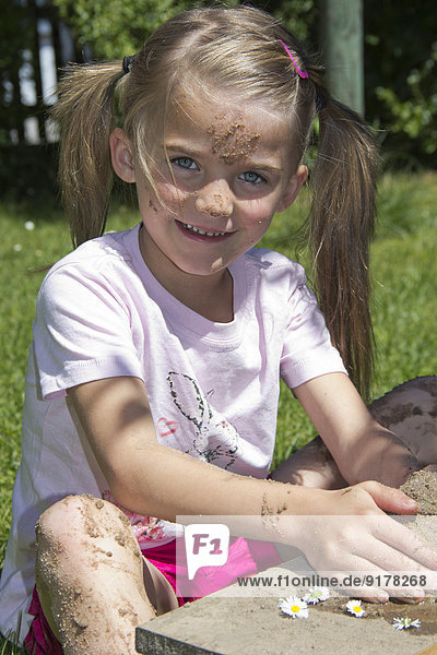 Porträt eines kleinen Mädchens beim Spielen mit Sand im Garten