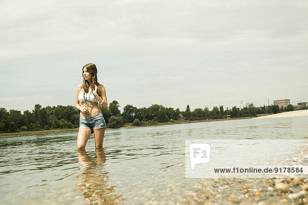 Young woman standing at waterside of Rhine river