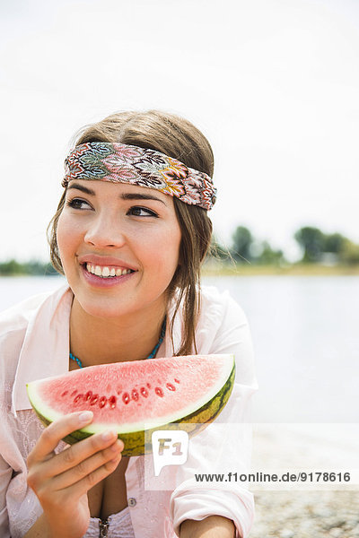 Portrait of young woman eating watermelon on the beach