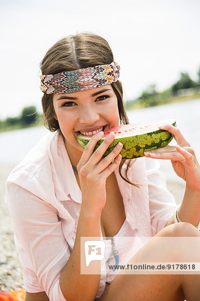 Porträt einer jungen Frau  die Wassermelone am Strand isst.