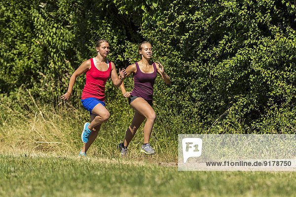 Zwei junge Frauen joggen auf dem Feldweg