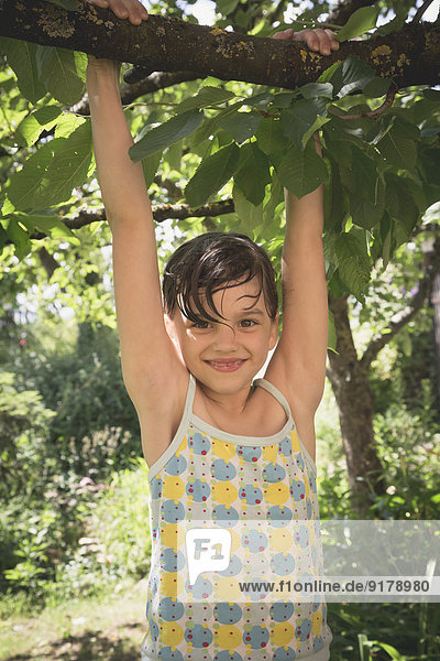 Portrait of smiling little girl climbing on tree