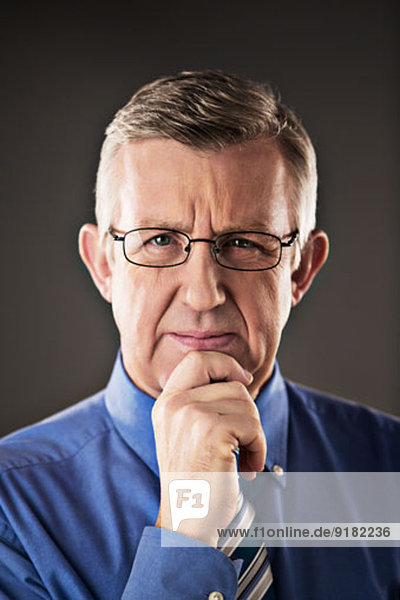 Portrait of confident businessman with hand on chin