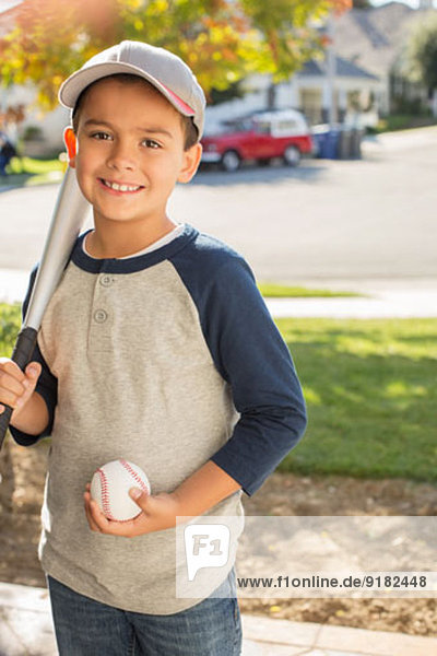 Portrait of smiling boy with baseball and bat