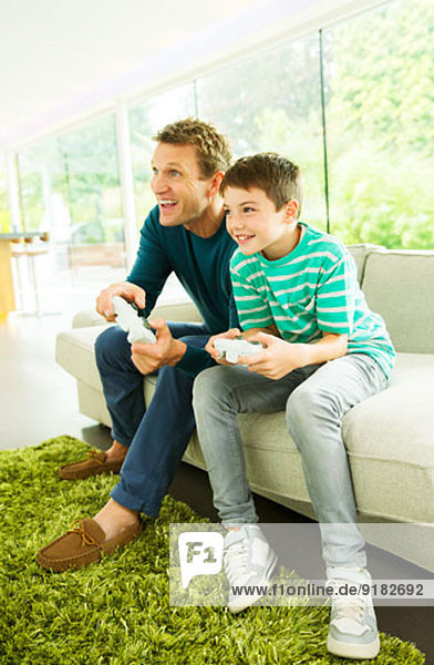Vater und Sohn spielen Videospiele im Wohnzimmer