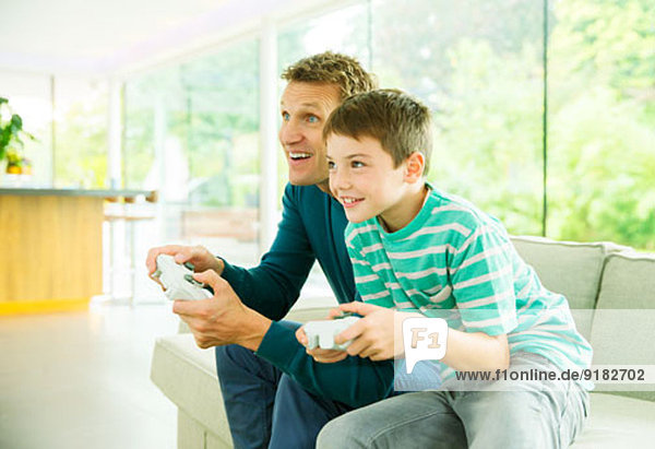 Vater und Sohn spielen Videospiele im Wohnzimmer
