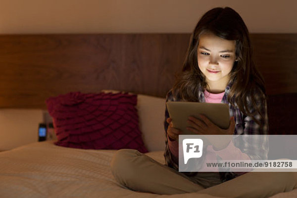 Mädchen mit digitalem Tablett auf dem Bett