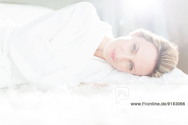 Frau im Bademantel auf dem Bett liegend