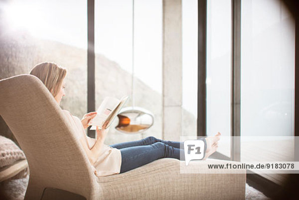 Frau liest auf Sofa im modernen Wohnzimmer