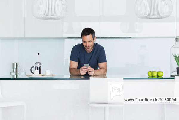 Man using cell phone in modern kitchen