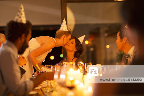 Frau küsst die Wange eines Freundes auf der Geburtstagsfeier