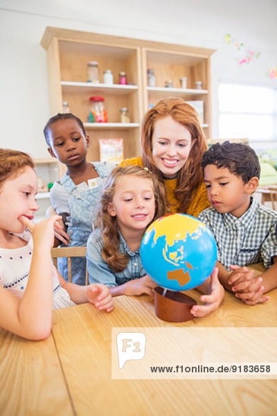 Schüler und Lehrer untersuchen den Globus im Klassenzimmer