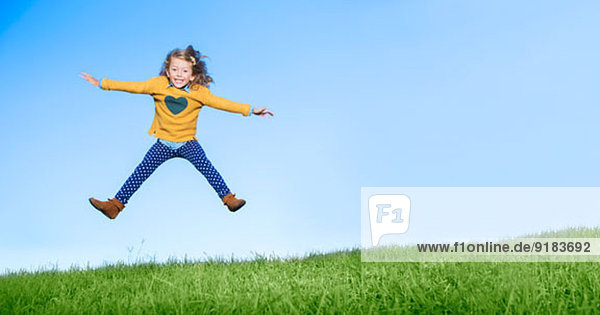Mädchen springen vor Freude auf einem grasbewachsenen Hügel