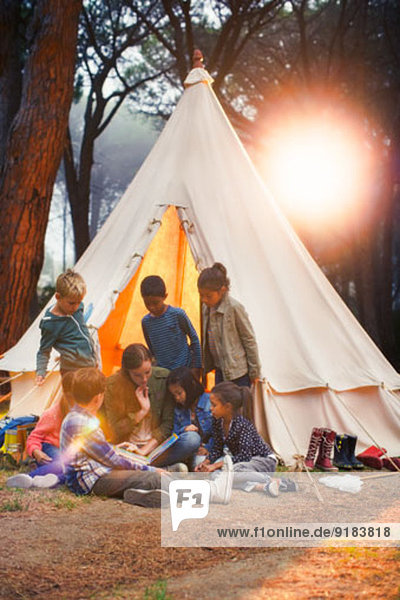 Schüler und Lehrer lesen am Tipi auf dem Campingplatz