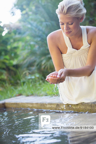 Frau beim Schröpfen von Poolwasser in der Hand