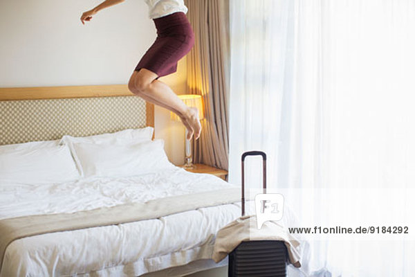Geschäftsfrau springt auf Bett im Hotelzimmer