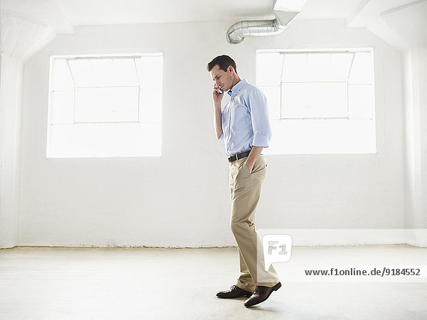 Caucasian businessman talking on cell phone in empty office