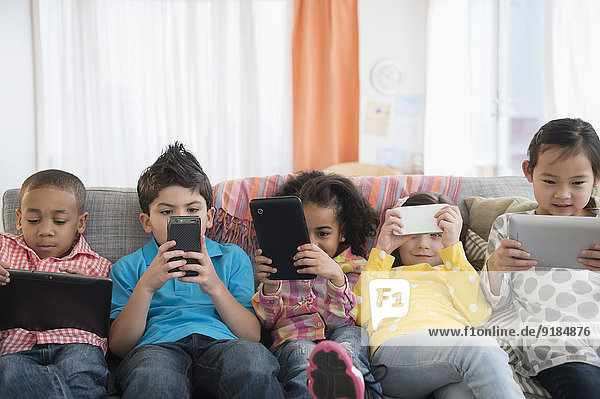 Children using technology on sofa