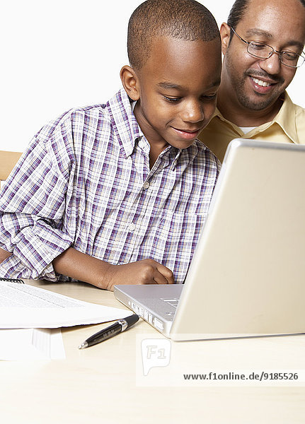 African American father and son using laptop