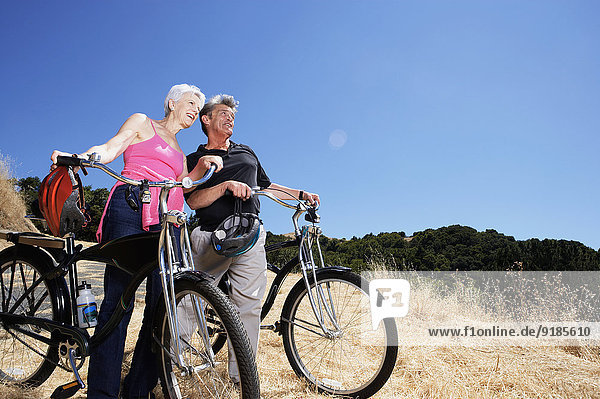 Senior Caucasian couple wheeling dirt bikes on hilltop
