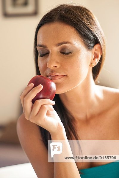 Portrait of young woman smelling red apple