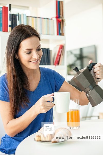 Young woman pouring coffee for breakfast