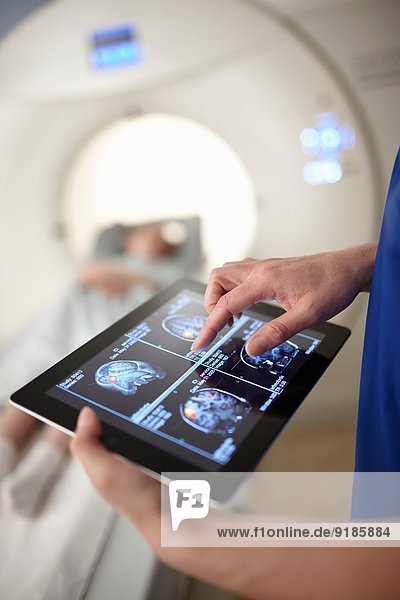 Röntgentechniker betrachtet Hirnscan-Bild auf digitalem Tablett