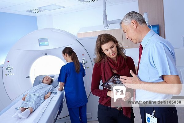 Arzt und Mutter sehen sich den Scan an  Mädchen geht in den CT-Scanner.